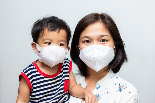 Asian mother holding her son wearing protective mask against covid 19 virus and PM 2.5 air pollution