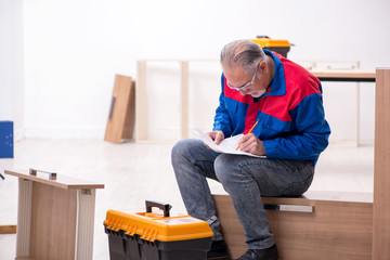 Old male carpenter working indoors
