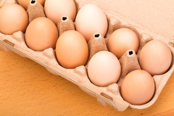 brown chicken eggs in an open cardboard box with eggs on a wooden table. Natural healthy food.