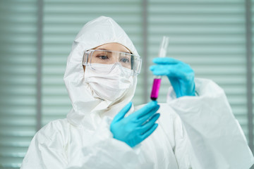 Woman Scientist researcher holding   liquid solution or biological tube for analysis and sampling of Covid-19.