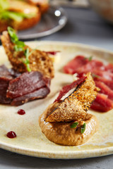 Meat appetizer in beige ceramic plate