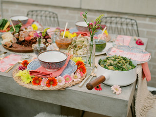 A table scape decorated with colorful plates and summer flowers  awaiting guests to arrive