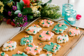 A tray of multi-colored vanilla cookies decorated with cream flowers