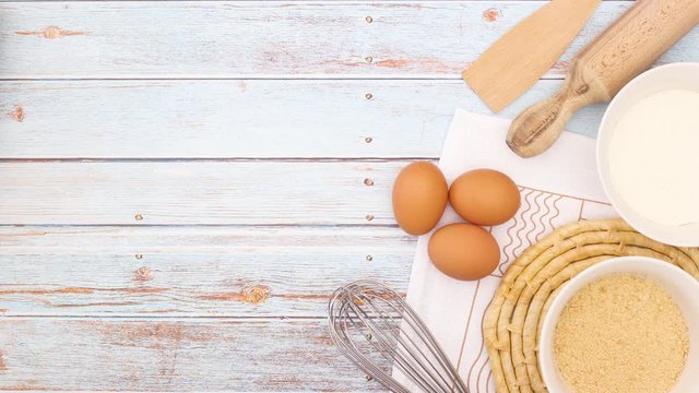 Cooking supplies, dishes and eggs appear on wooden table - Stop motion 