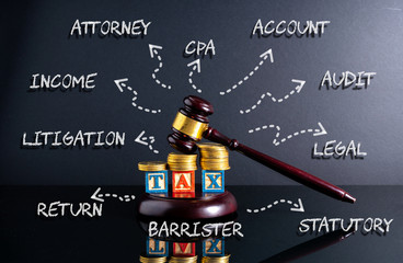 Gavel hammer and stacking coins and tax letter cube with low light view.