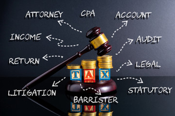 Gavel hammer and stacking coins and tax letter cube with low light view.