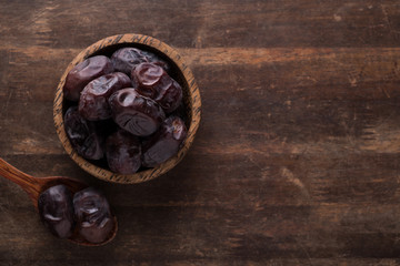 Fototapeta na wymiar sweet and delicious fresh dates inside wooden bowl in top of dark wooden table. dates is popular during ramadan month as energy booster