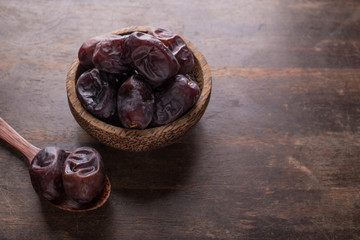 sweet and delicious fresh dates inside wooden bowl in top of dark wooden table. dates is popular during ramadan month as energy booster