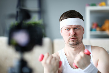 Serious Vlogger Doing Exercise with Dumbbells. Concentrated Sportsman Record Video on Digital Camcorder for Sport Vlog. Beard Man Practice Aerobic for Hands. Digital Camera Shooting Fitness Trainer
