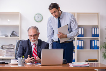 Old boss and young male employee in the office