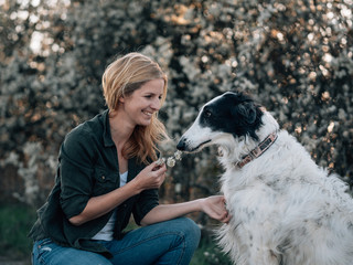 Woman with her dog playing with flowers - 340824489