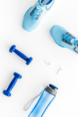 Sport equipment. Sneakers, dumbbells and water on white table top view flat-lay