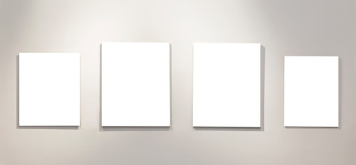 Four empty isolated on white paintings on the wall with gallery lighting. Space for text.