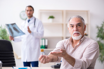 Fototapeta premium Young male doctor and old patient in antismoking concept