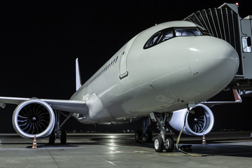 Fototapeta na wymiar Close-up a white passenger aircraft at the jetway on an airport night apron