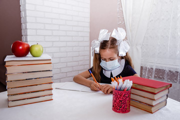 A masked schoolgirl does her homework. coronavirus. self-isolation