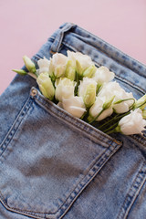 White eustoma flowers in a pocket jeans