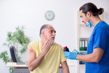 Fototapeta premium Injured old man visiting young male doctor traumatologist