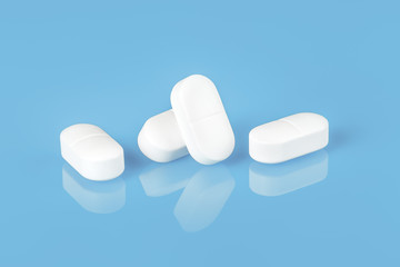 Several white tablets or pills reflected on blue glass. copy space close up view. Medication safe...