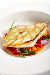 Fried flounder fillet on baked potato slices