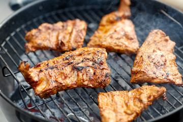 cooking, culinary and food concept - close up of barbecue meat roasting on brazier grill outdoors