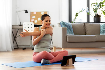 sport, fitness and healthy lifestyle concept - happy smiling young african american woman with tablet pc computer stretching arm at home