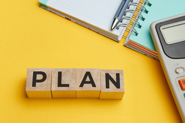 PLAN word from wooden blocks on a yellow background
