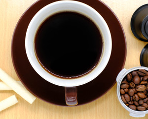 Coffee cup on wooden kitchen table. Top view with morning sunlight