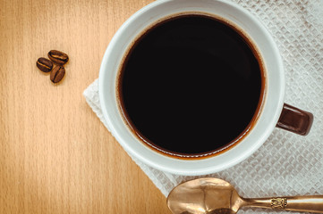 Coffee cup on wooden kitchen table. Top view with morning sunlight