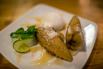 Deep fried banana dessert with ice cream scoop, lime and syrup