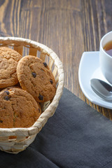 oatmeal cookies with chocolate chips in a basket on a wooden table