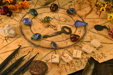 Ouija spiritual board with runes and magic objects on witch table.