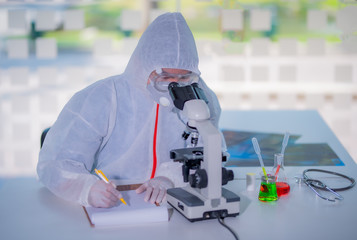 Male scientist testing experiment in a science lab where he holding scientific test tube full of...