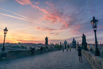 Charles bridge in Prague at sunrise with photographers and tourists