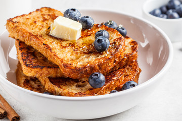 French toasts with berries and honey in white plate.