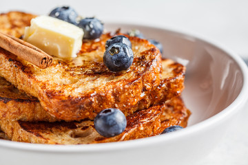 French toasts with berries and honey in white plate.
