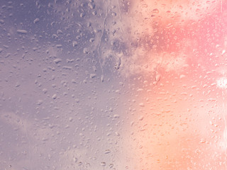 Wet window with rain drops and a cloudy sky outside.