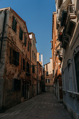 Fototapeta na wymiar A narrow street in Venice between ancient stone houses on a Sunny day | VENICE, ITALY - 16 SEPTEMBER 2018. 