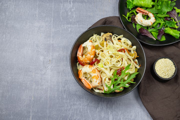 Stir fry noodles with vegetables and shrimps in bowl. Top view. Copy space.