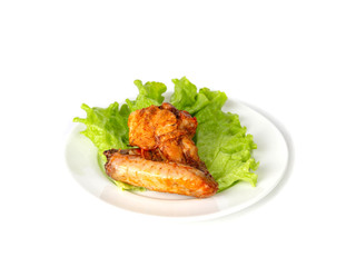 Fried chicken wing on a plate with a sheet of fresh salad
