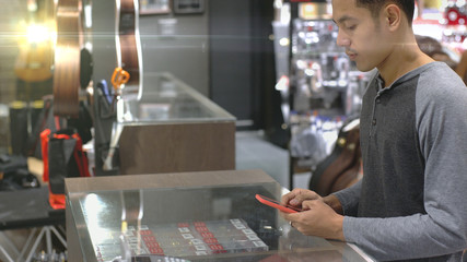 An upwardly mobile Asian Muslim man using a mobile phone - smartwatch to pay for a product at a sale terminal with nfc identification payment for verification and authentication