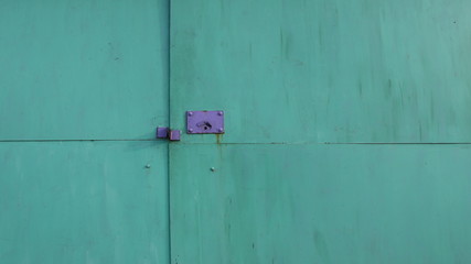 metal greenish garage door with lilac plate and keyhole