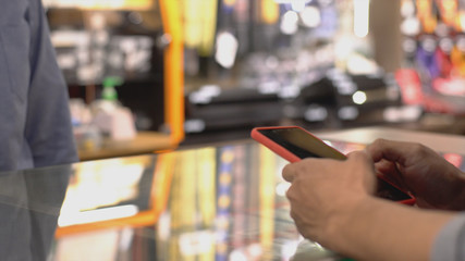 An upwardly mobile Asian Muslim man using a mobile phone - smartwatch to pay for a product at a sale terminal with nfc identification payment for verification and authentication