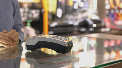 An upwardly mobile Asian Muslim man using a mobile phone - smartwatch to pay for a product at a sale terminal with nfc identification payment for verification and authentication