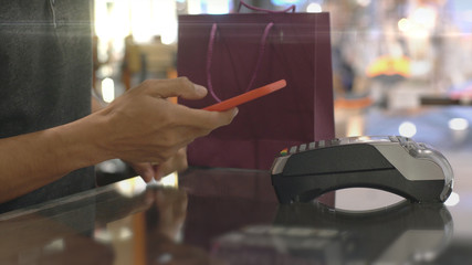 An upwardly mobile Asian Muslim man using a mobile phone - smartwatch to pay for a product at a sale terminal with nfc identification payment for verification and authentication