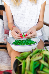 Woman preparing fresh organic peas and taking it out from a shell.