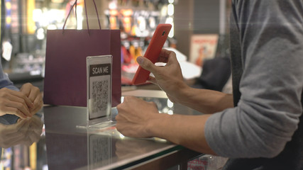 An upwardly mobile Asian Muslim man using a mobile phone - smartwatch to pay for a product at a sale terminal with nfc identification payment for verification and authentication