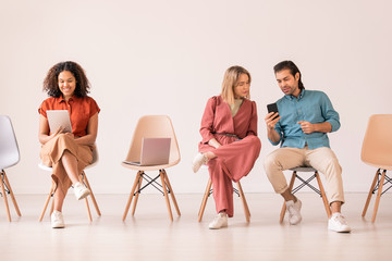 Obraz premium Modern young man showing new convenient smartphone app to girl while black woman talking via video chat on tablet