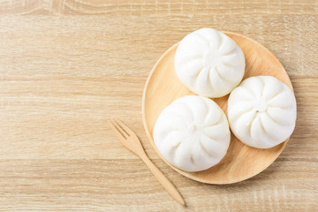 Steamed buns stuffed with minced pork on wooden plate with fork on wooden table, Asian food, Top...