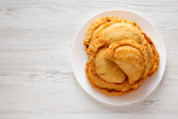 Homemade Deep Fried Italian Panzerotti Calzone with sauce on a white plate on a white wooden background, top view. Flat lay, overhead, from above. Copy space.